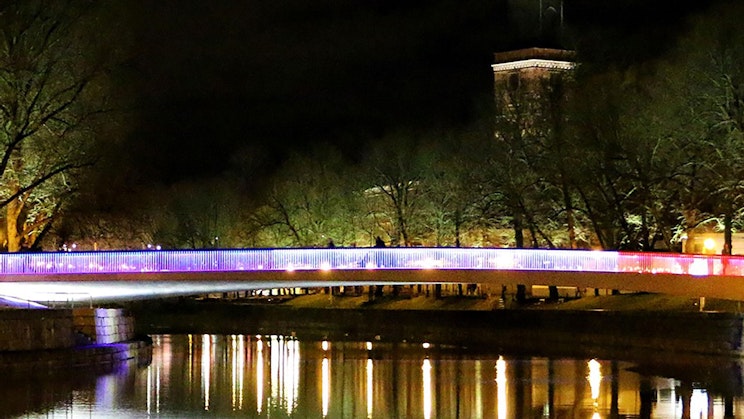 silta joen yli yöllä kellotornin taustalla