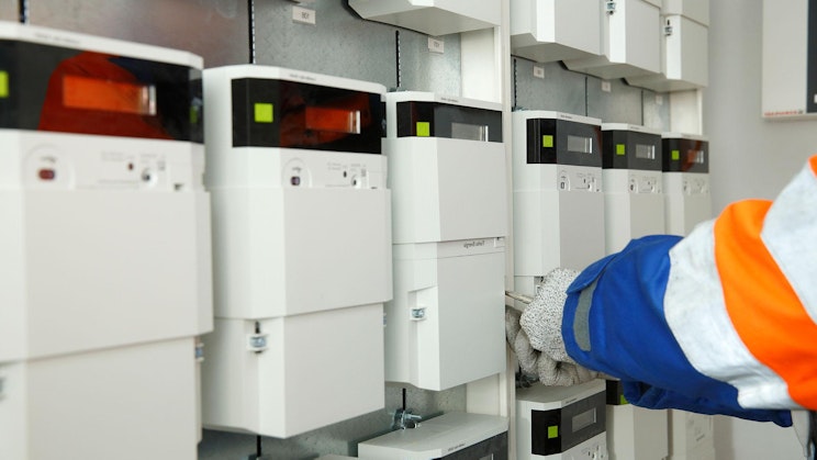 oranssinvalkoiseen takkiin pukeutunut henkilö poimii sähkölaitteita