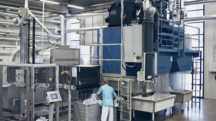 nainen seisoo koneen edessä tehtaalla