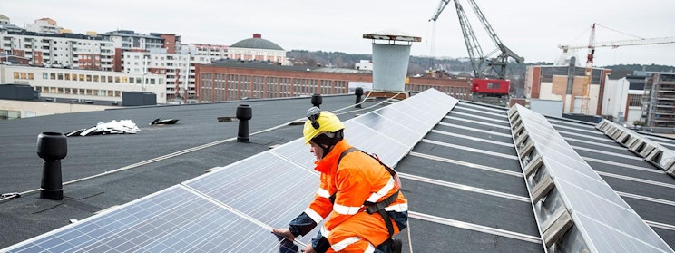 mies katolla asentamassa aurinkopaneeleja