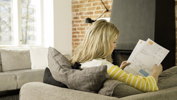 nainen on sohvalla lukemassa paperia