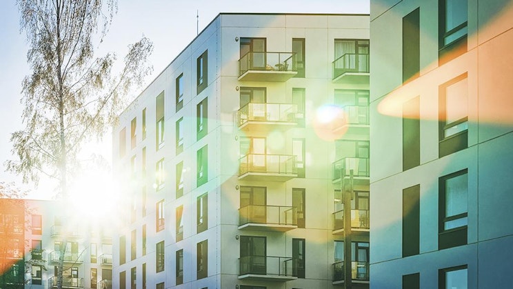 aurinko paistaa kirkkaasti monikerroksisen rakennuksen ikkunoista