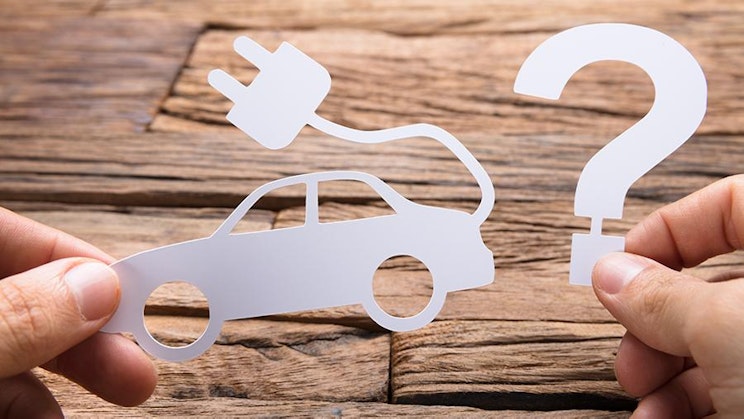 kaksi kättä pitelevät paperileikkausta autosta ja kysymysmerkkiä