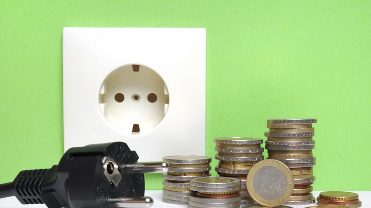 Pistorasian edessä kasa kolikoita ja töpseli