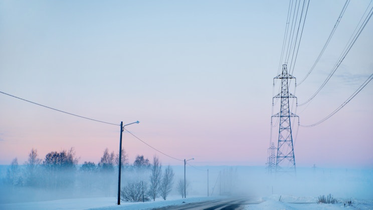 Kuvassa sumuinen maisema tiestä ja sähköverkoista