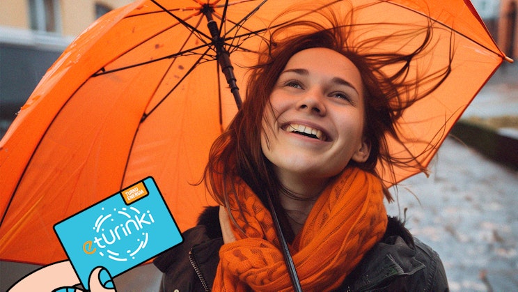 Tuulisessa sadekelissä iloinen tyttö oranssin sateenvarjon kanssa.
