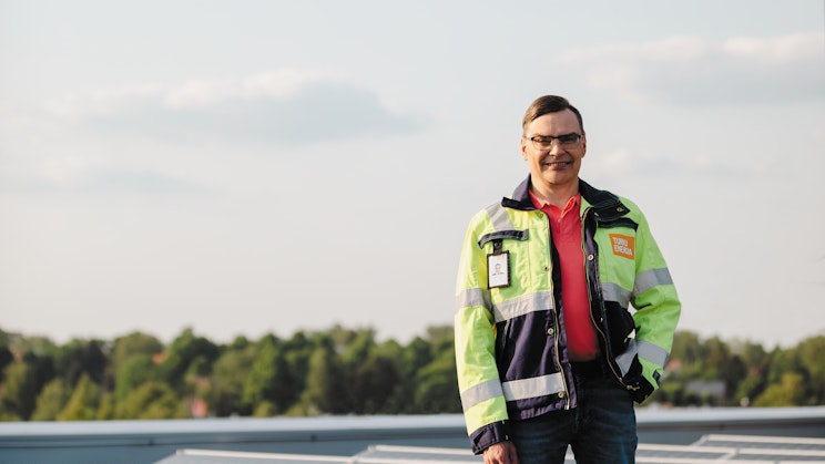 Jari Hallivuori seisoo katolla aurinkopaneelien kanssa