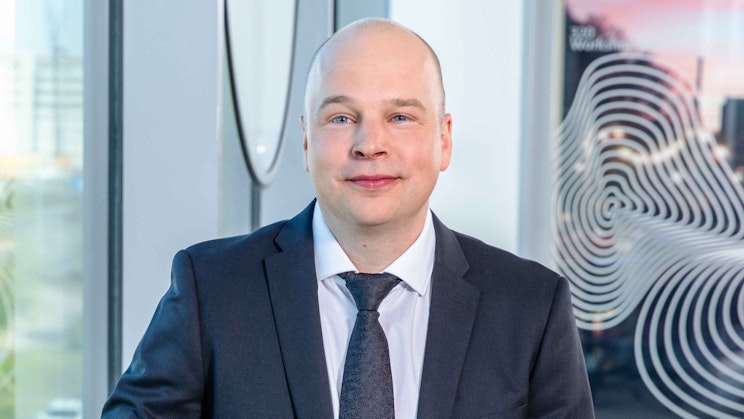 Kuvassa pukumies poseeraa kameralle