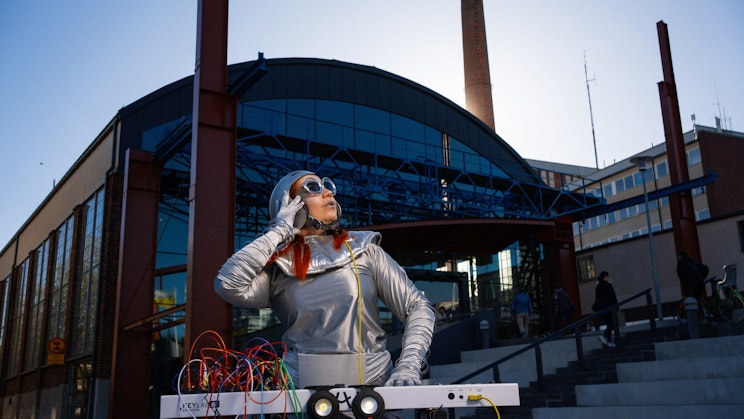 Nainen hopeisissa vaatteissa dj pöydän äärellä