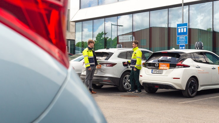 Kuvassa kaksi henkilöä keskustelee autojen vieressä