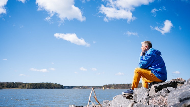 Miesoletettu istuu kalliolla ja ihailee merimaisemaa