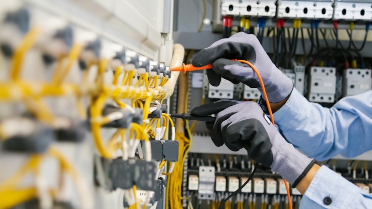 ihminen turvahanskoilla tarkistamassa sähkömittareiden sähkövarausta