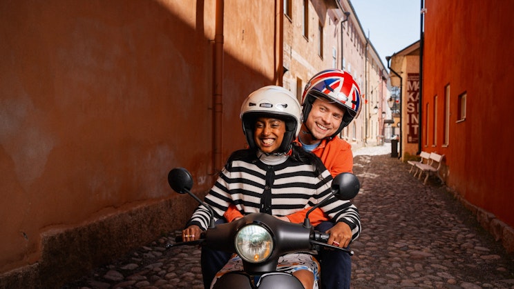 Nainen ja mies ajavat sähköskootterilla kapealla kujalla Turussa.