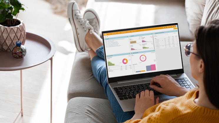 Nainen istuu sohvalla tietokone sylissään