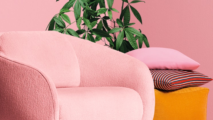 Pinkki huone jossa on pinkki nojatuoli ja viherkasvi