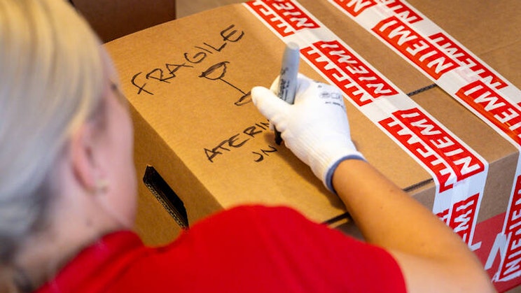 Naisoletettu kirjoittaa pahvilaatikkoon tussilla