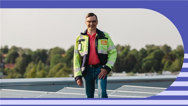 Henkilö seisoo katolla aurinkopaneelien seassa