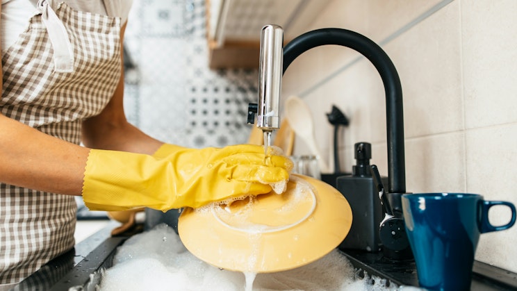 Kuvassa henkilö tiskaa astioita tiskialtaassa.