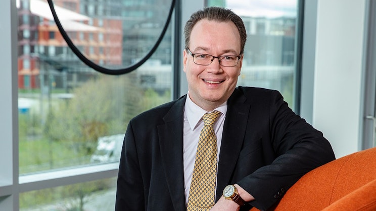 Miesoletettu nojaa nojatuoliin ja hymyilee kameralle