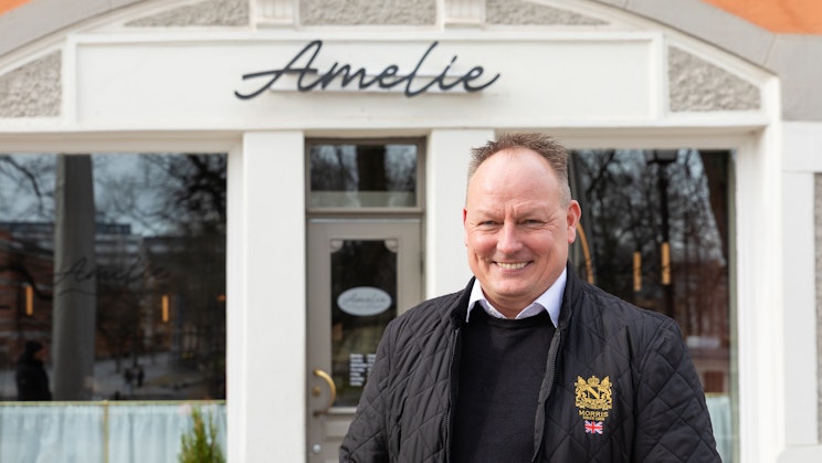 Kuvassa miesoletettu hymyilee kameralle ravintola Amelien edessä