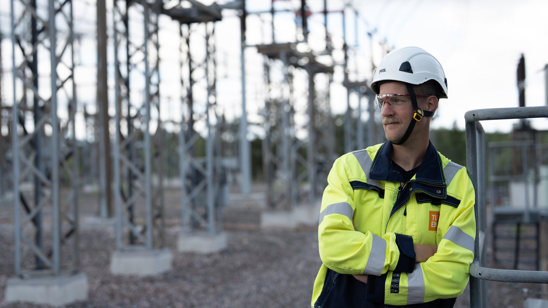 Turku Energia Söhköverkkojen työntekijä seisoo sähköaseman ulkorakenteiden keskellä.
