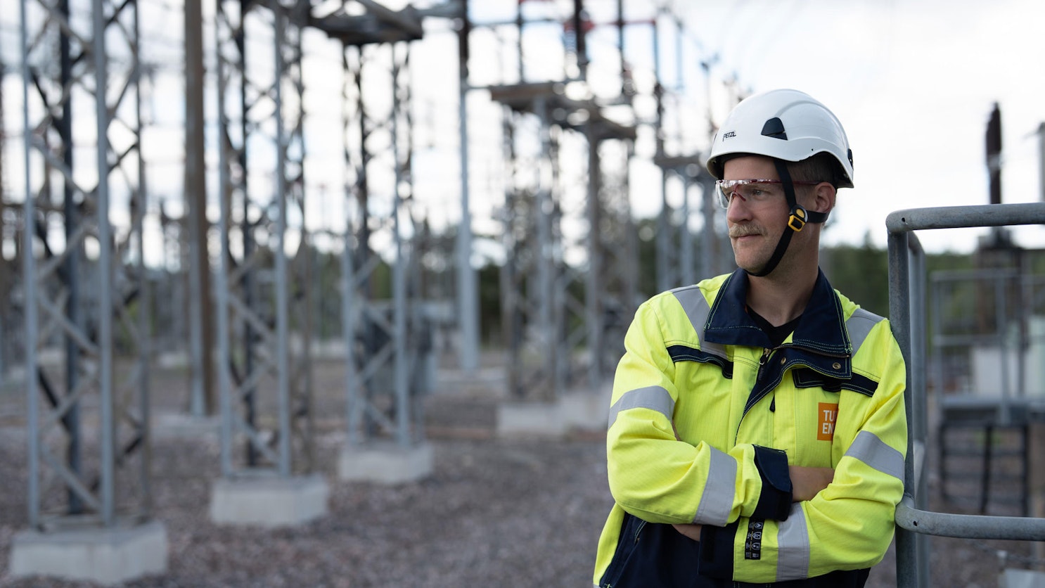 Turku Energia Söhköverkkojen työntekijä seisoo sähköaseman ulkorakenteiden keskellä.