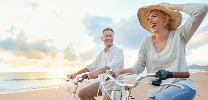 man and woman riding bikes on the beach
