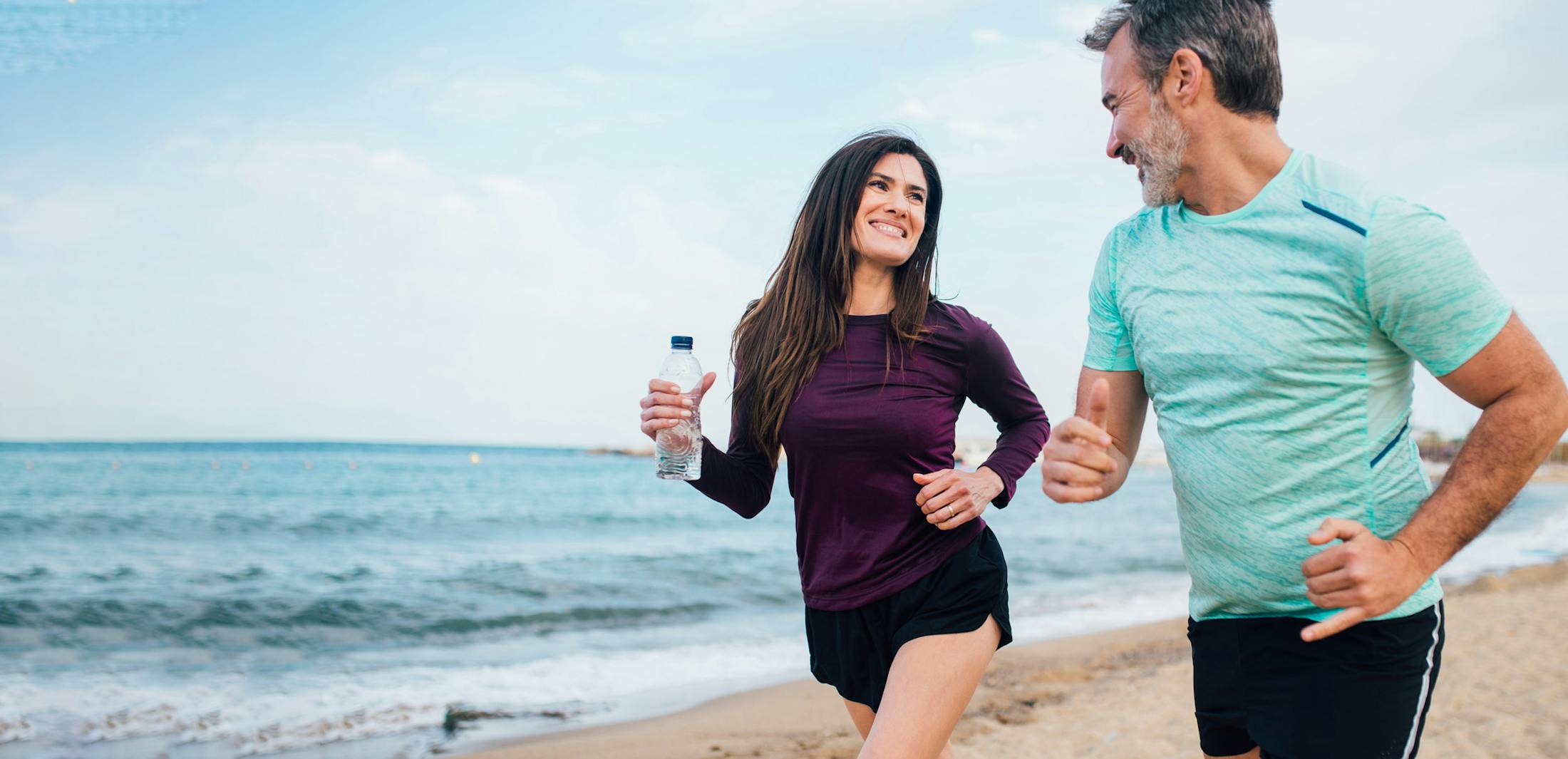 man and woman running on the beach