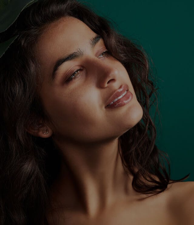 Closeup of a woman's face in front of a blue background.