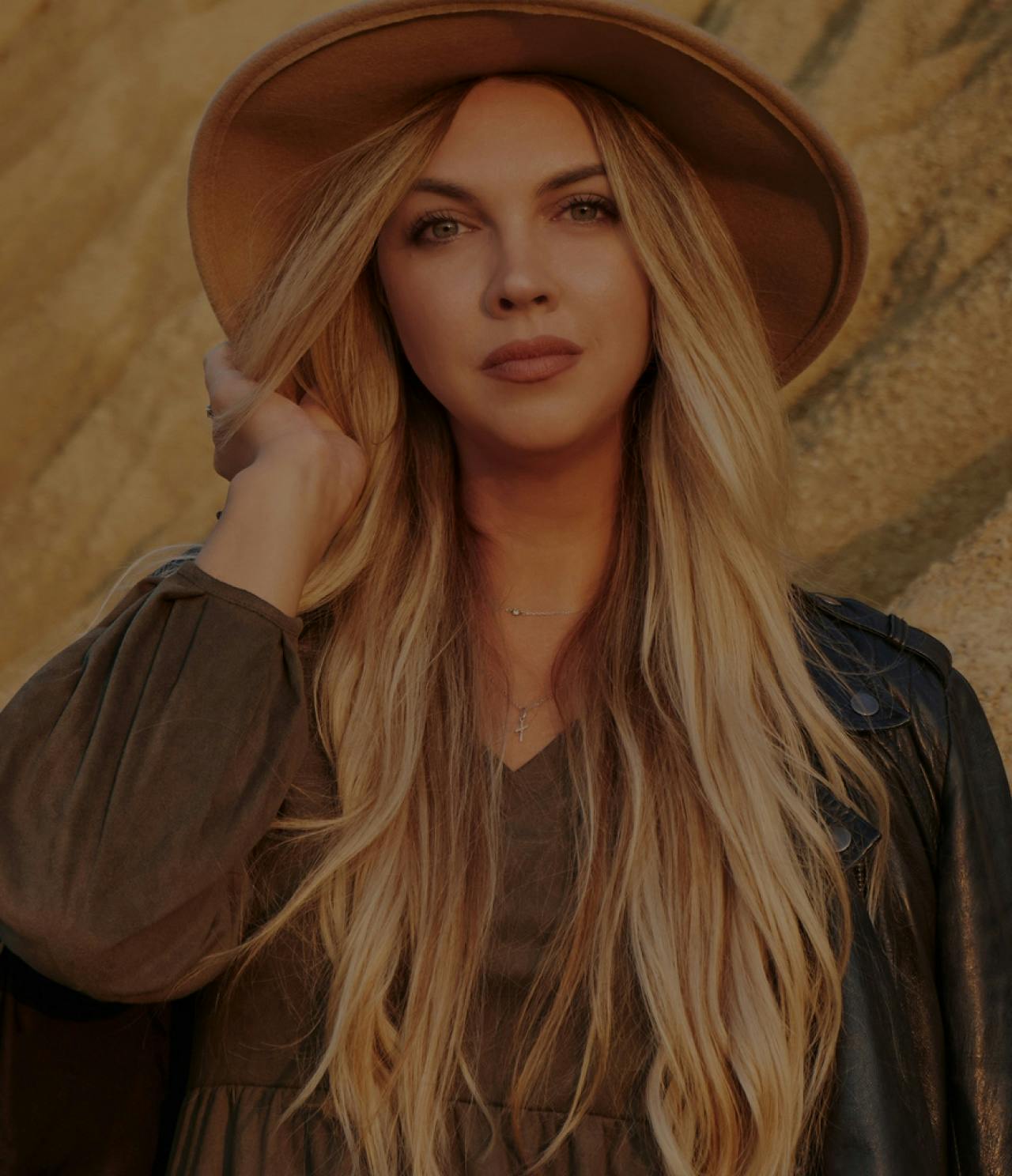 Model posing touching her brown hat.