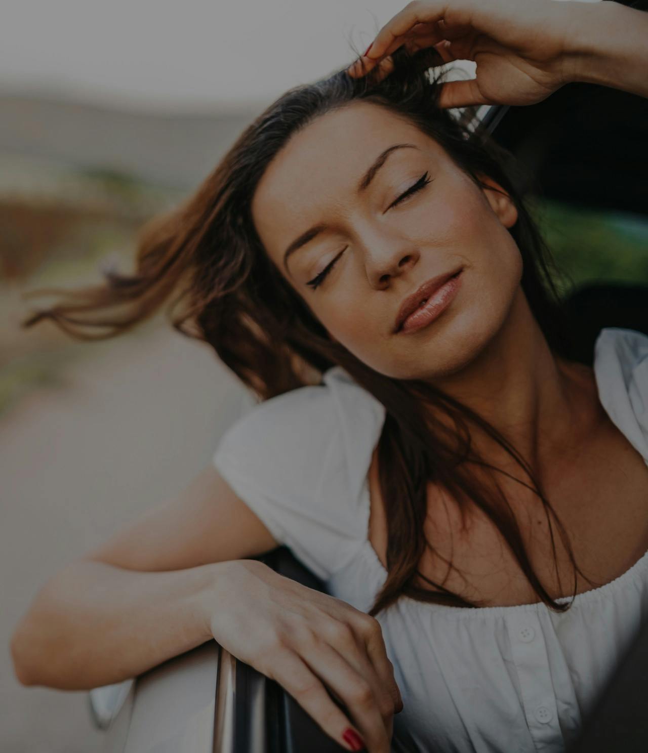 Woman with her head out of a car window and her eyes closed.