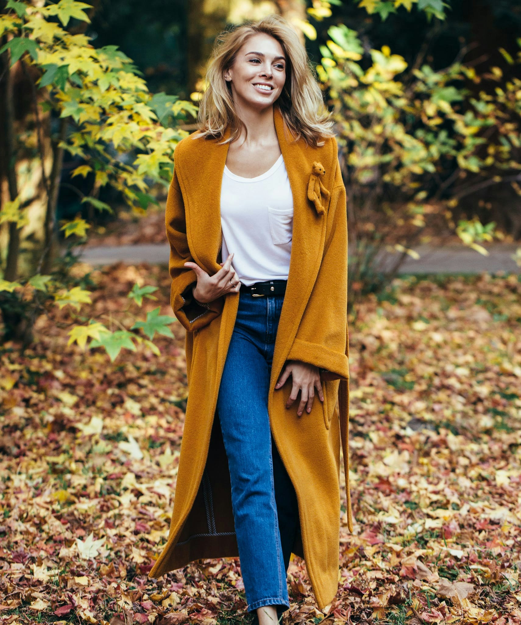 Smiling woman walking through fall foliage.