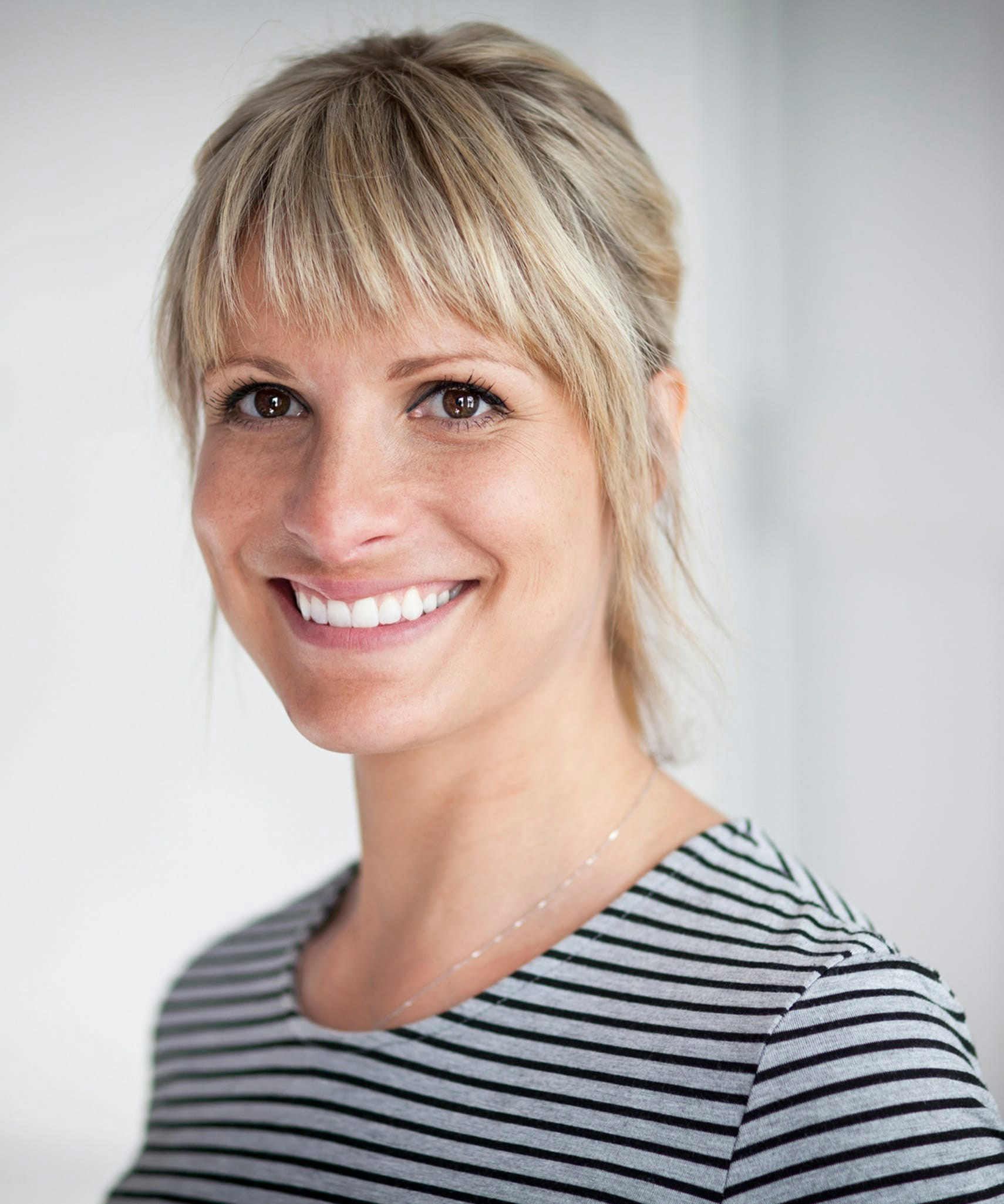 Wmiling woman with freckles and a striped shirt.