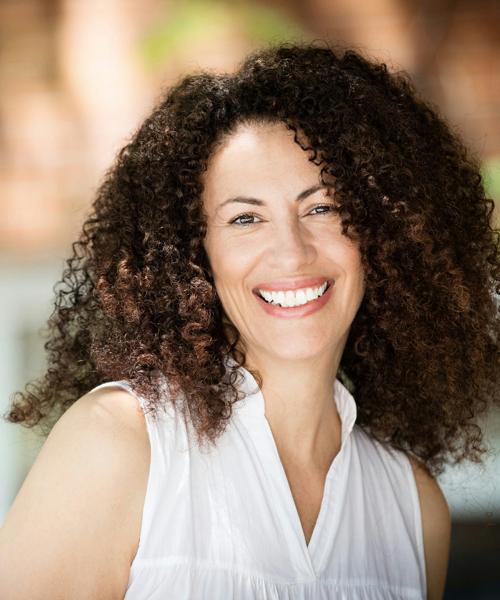 Woman with curly hair wearing white blouse