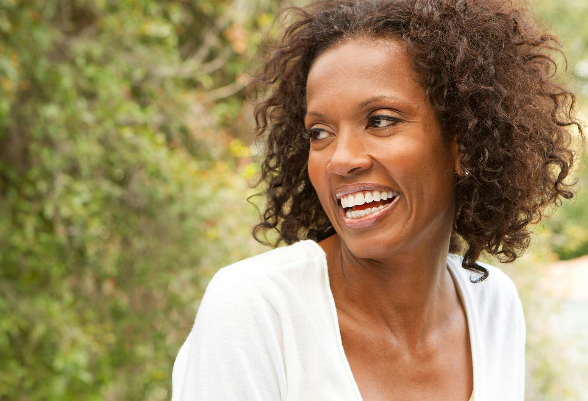 Smiling woman in white shirt looking over left shoulder.