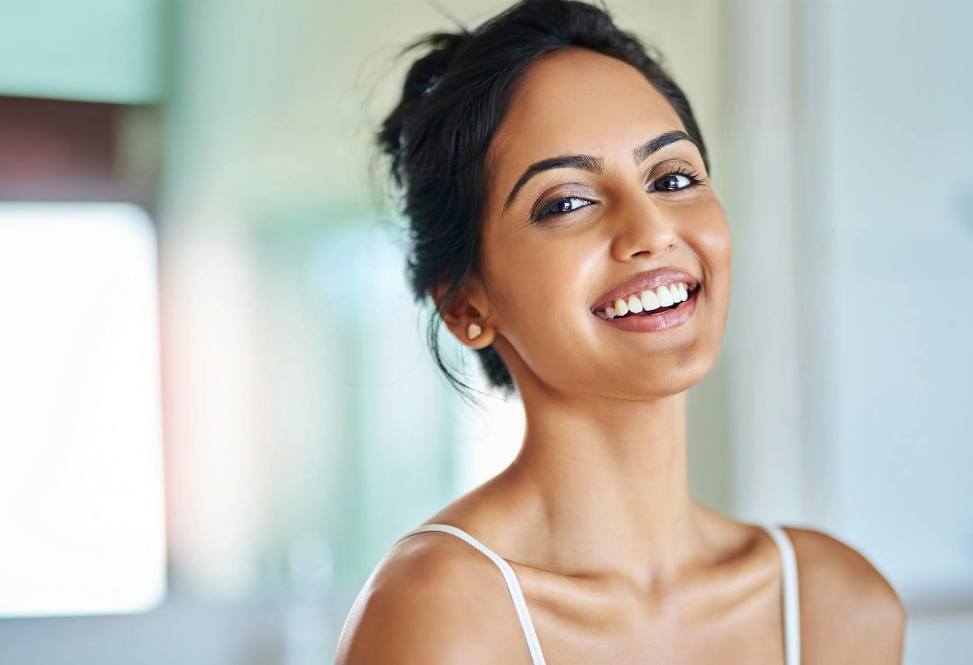 Smiling woman wearing spaghetti strap top.