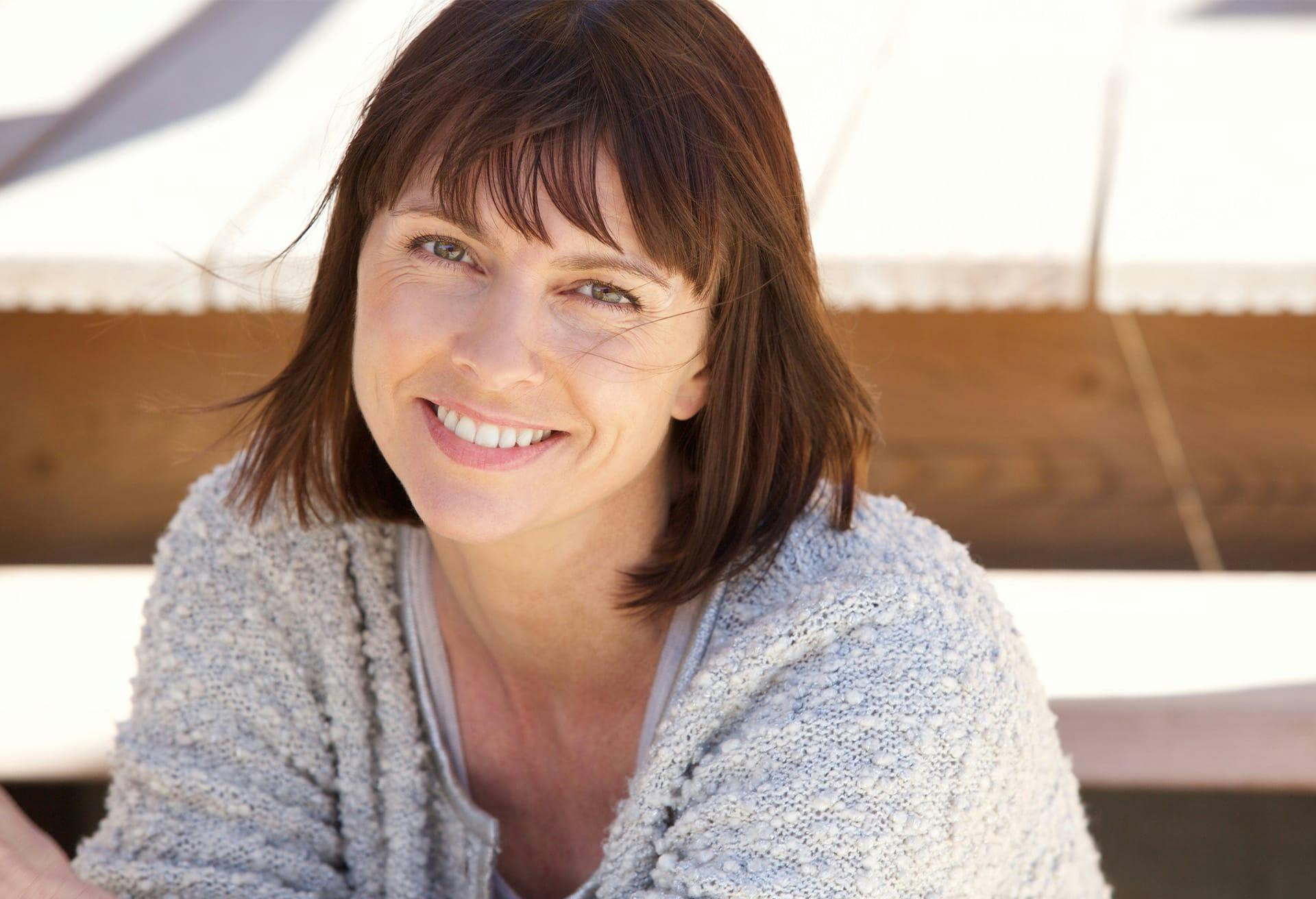 Smiling woman in grey sweater.