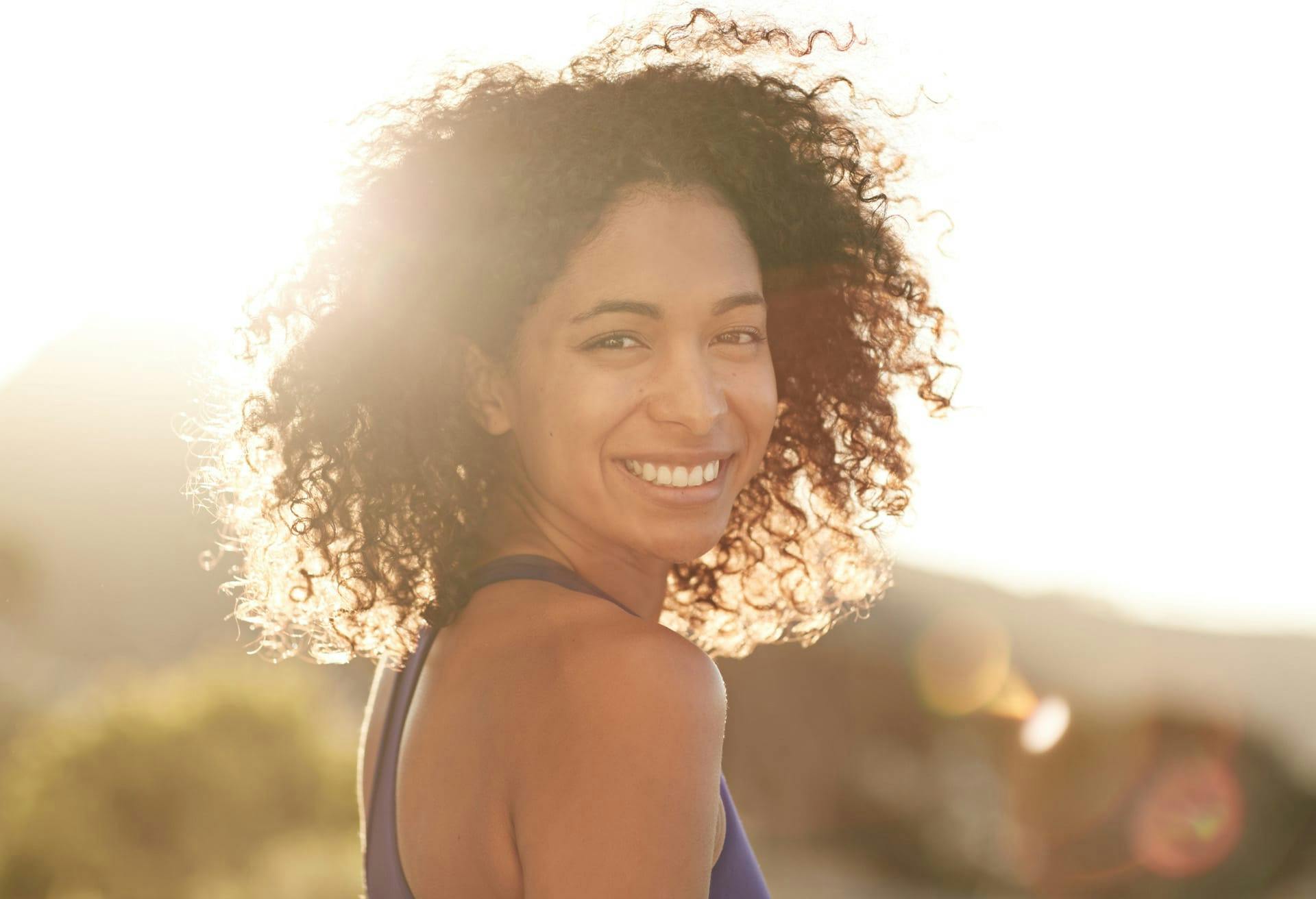 Woman with dark curly hair smiling