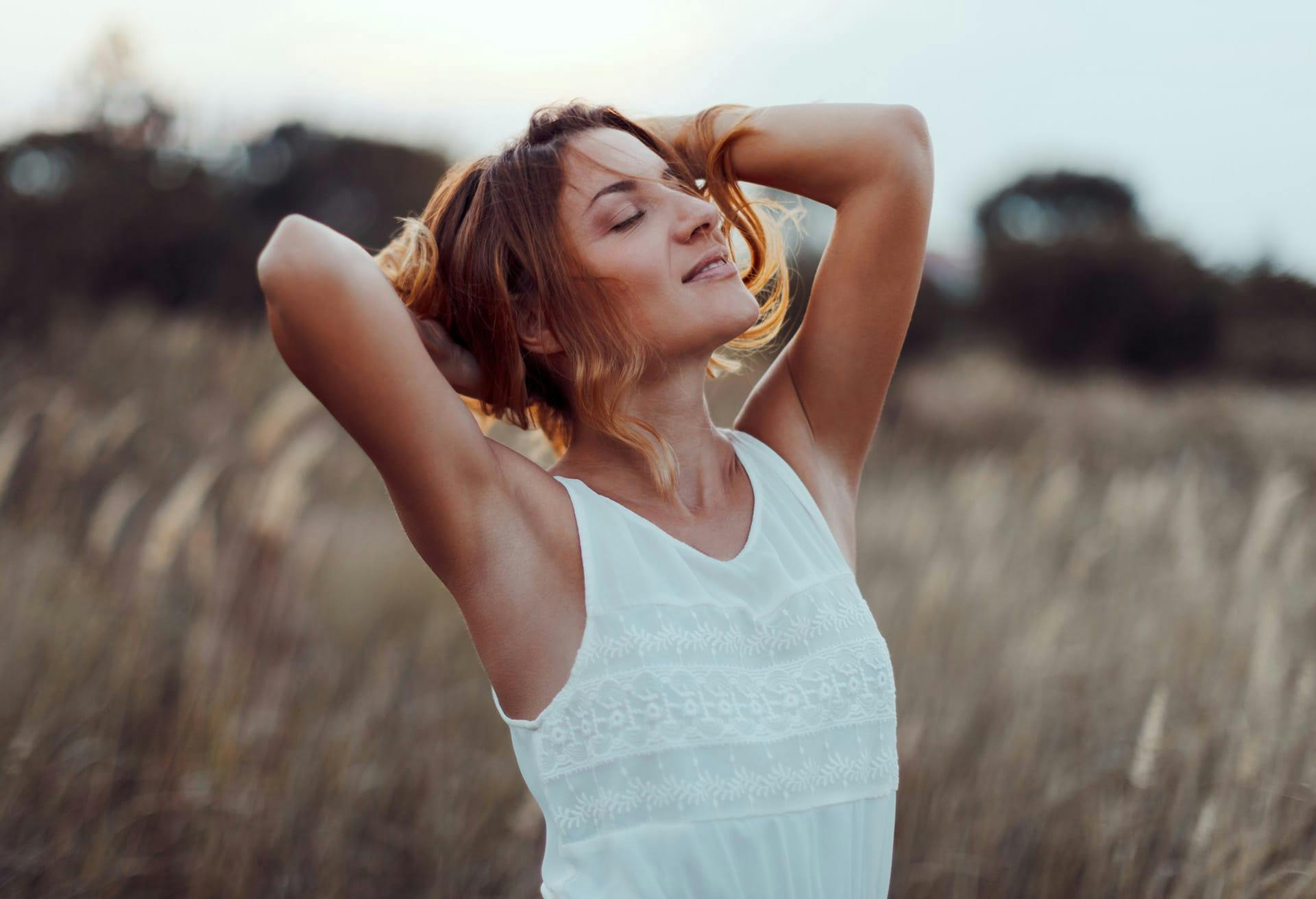 Smiling woman enjoying sun in field.
