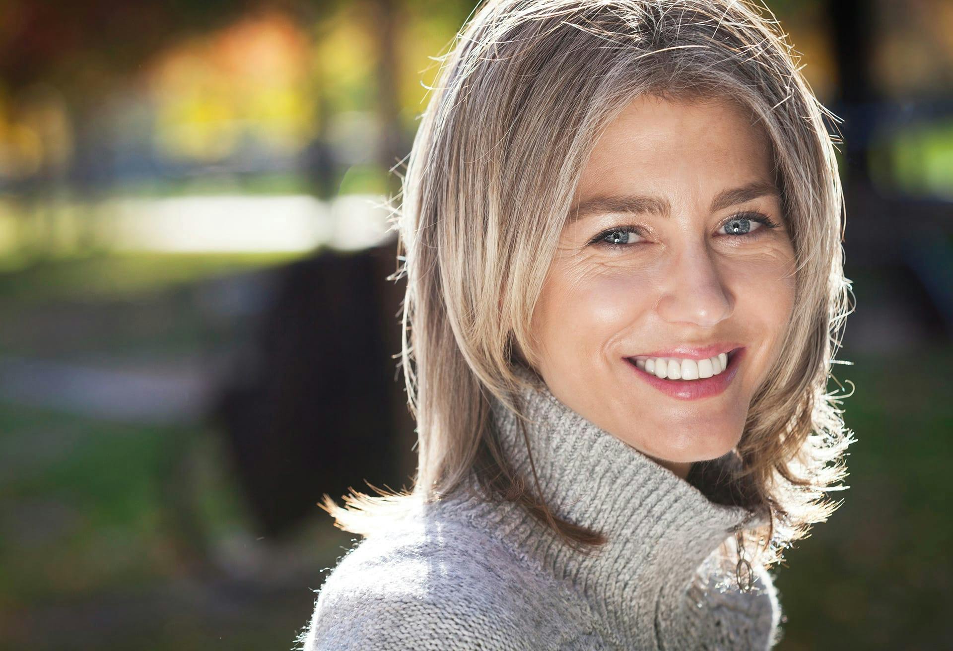 Smiling woman in grey turtleneck.