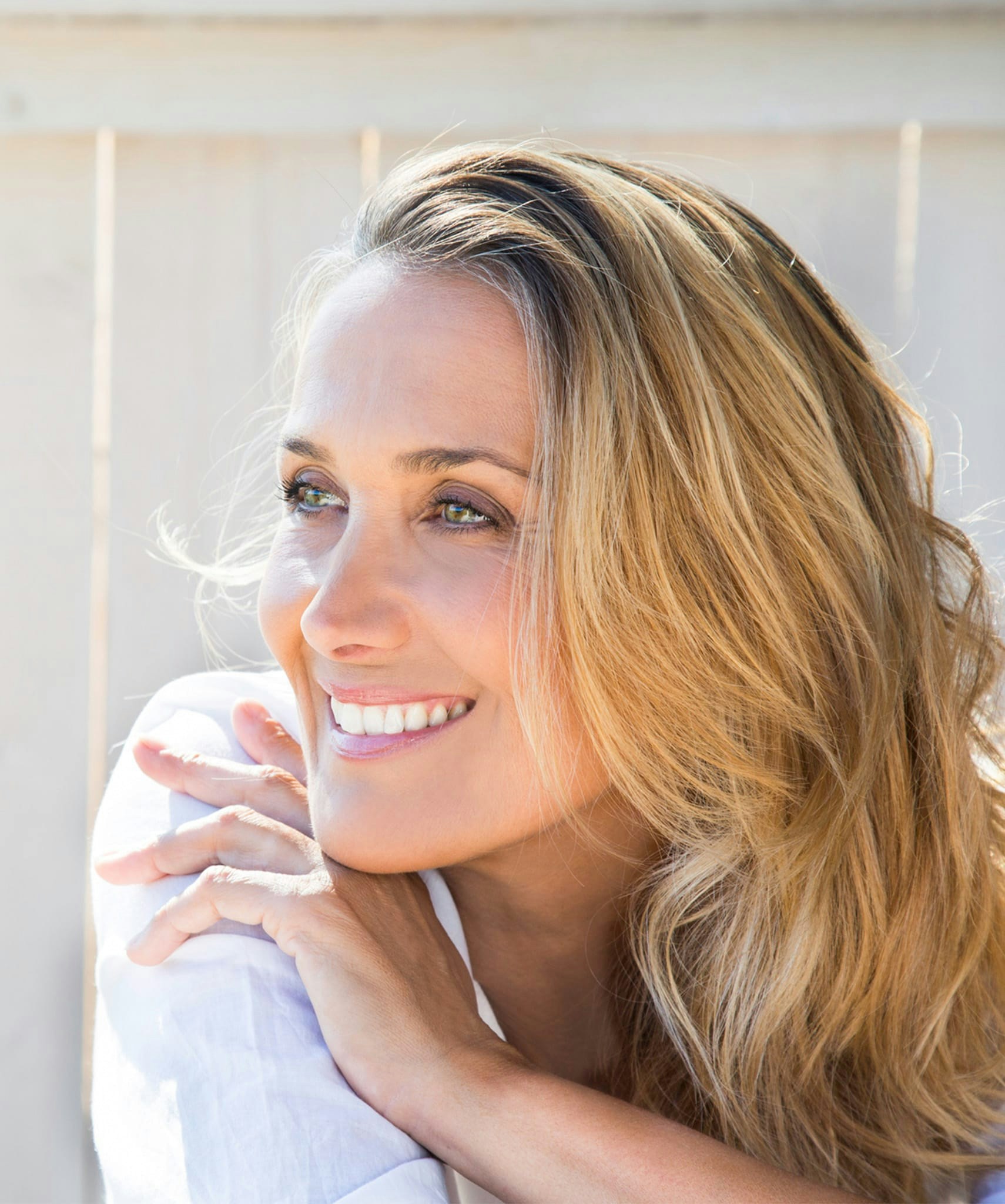 Smiling woman in white blouse looking over shoulder.