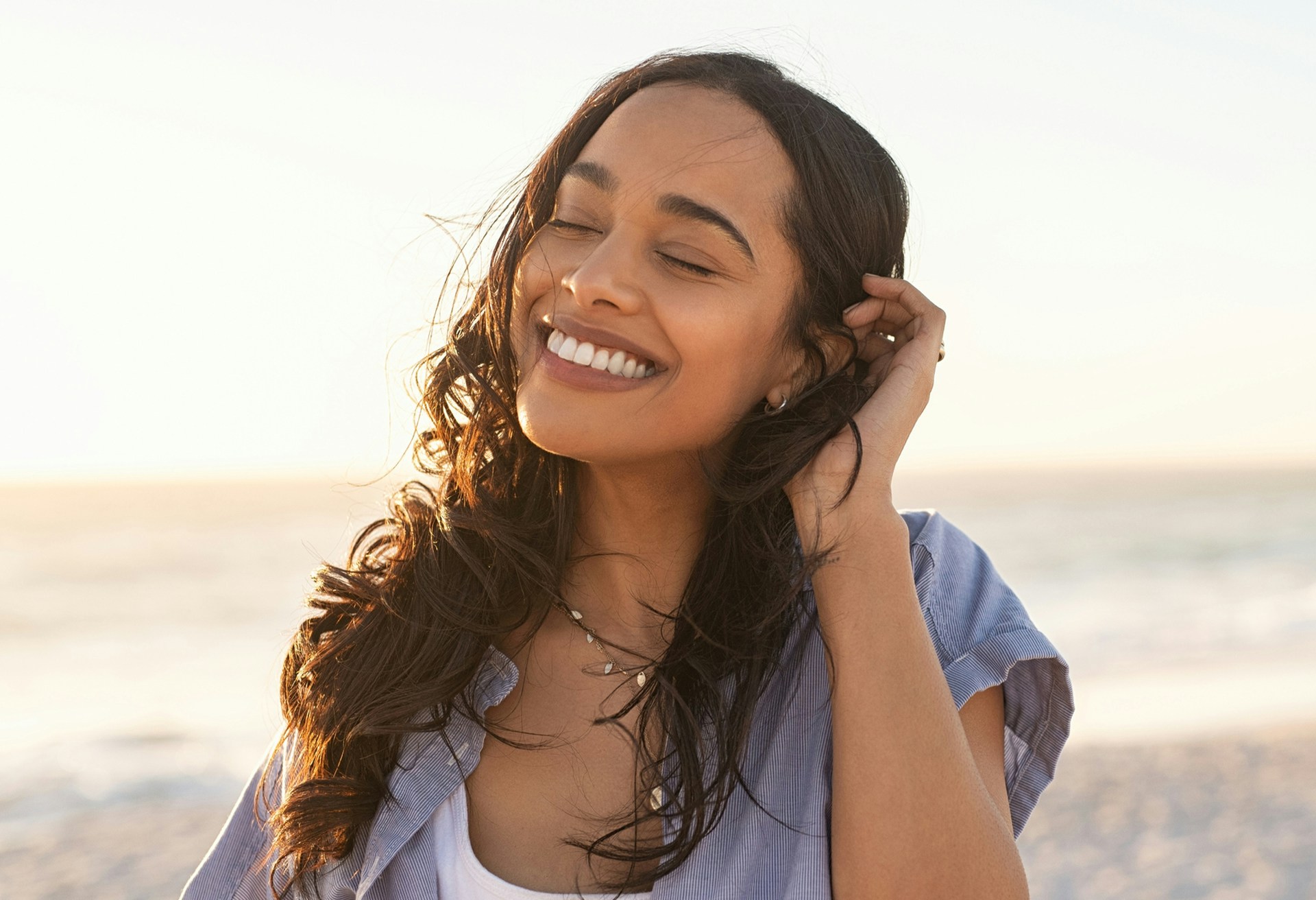 Woman in blue button up smiling outside