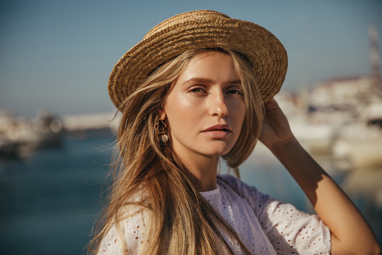 Young blonde woman wearing a hat outside
