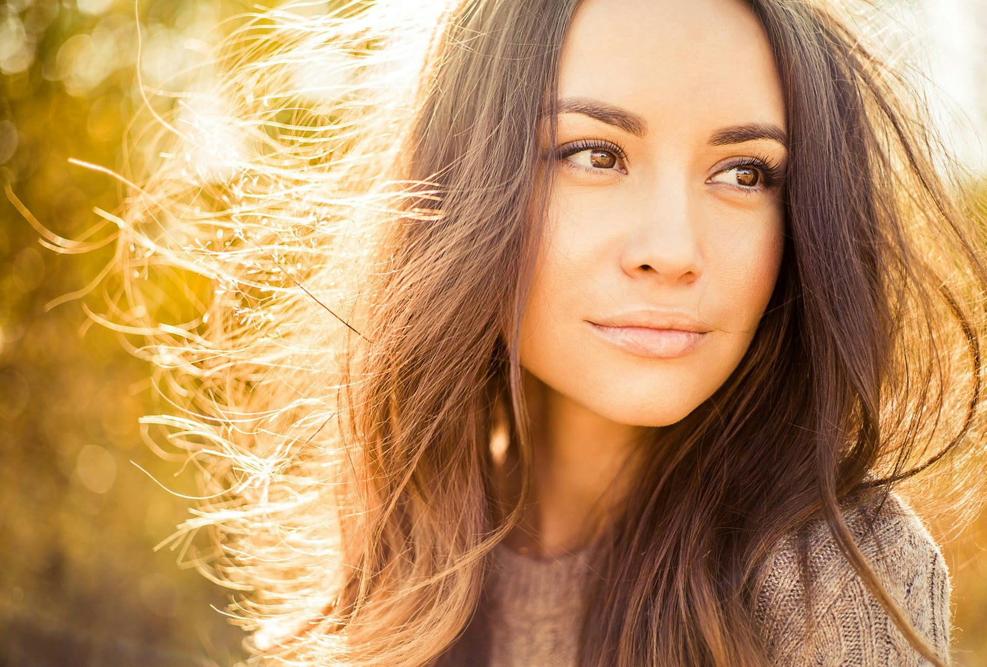 Beautiful woman with long brown hair standing in the sunlight