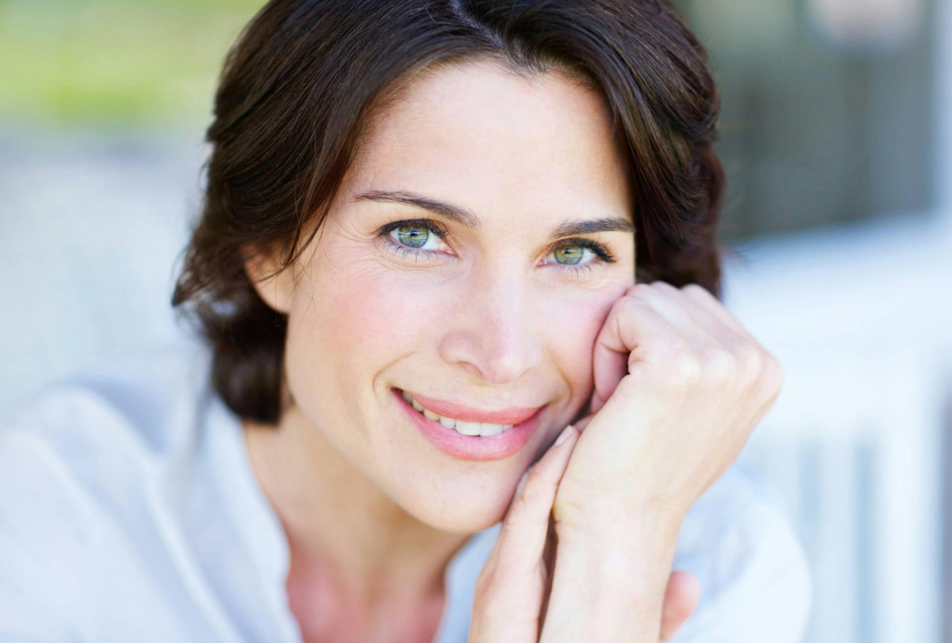 Woman with dark hair and green eyes smiling