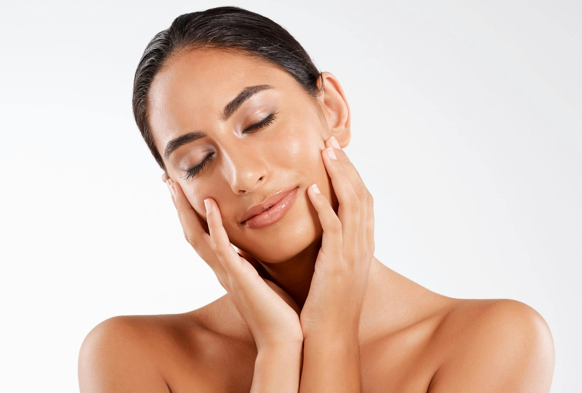Woman with clear skin closing her eyes and touching her face