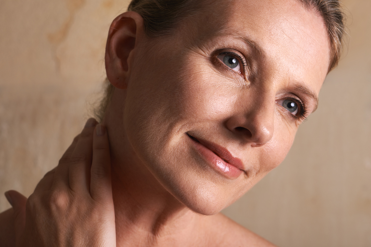 Mature woman touching neck and smiling softly