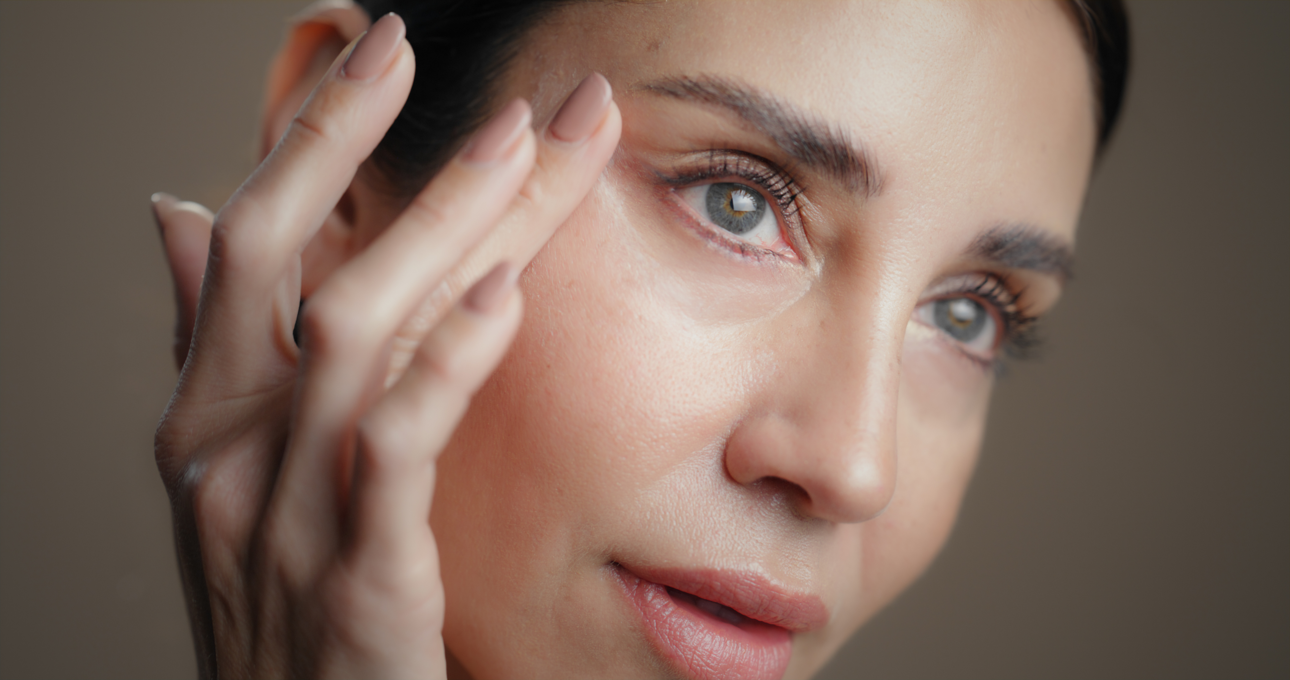 Woman gently touching the skin around her eyes and cheek.