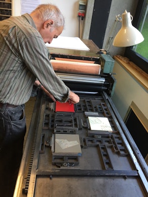 Ein Mann bereitet in einer Druckwerkstatt eine Lithografieplatte vor.