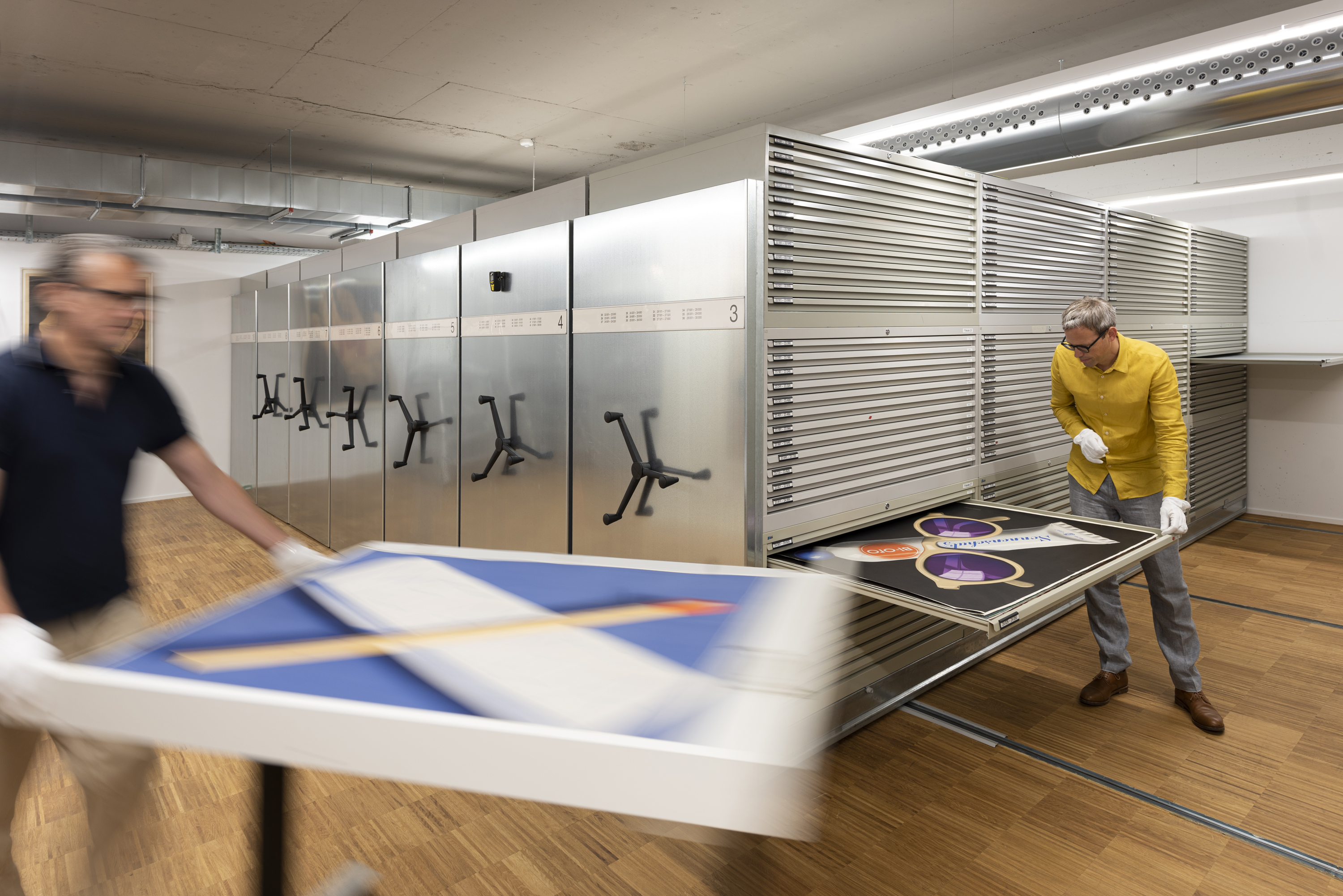 Mitarbeiter heben Plakate aus dem Archiv aus